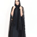 A luxurious abaya made of shimmering foil-finish chiffon, featuring black lace embellished with sparkling stones.